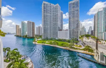 Miami River mouth with the Brickell skyline, waterfront park, and Biscayne Bay beyond.