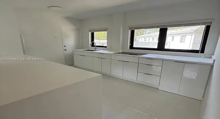 Kitchen featuring gloss-finish cabinetry, solid-surface countertops, tile flooring, and black-framed windows