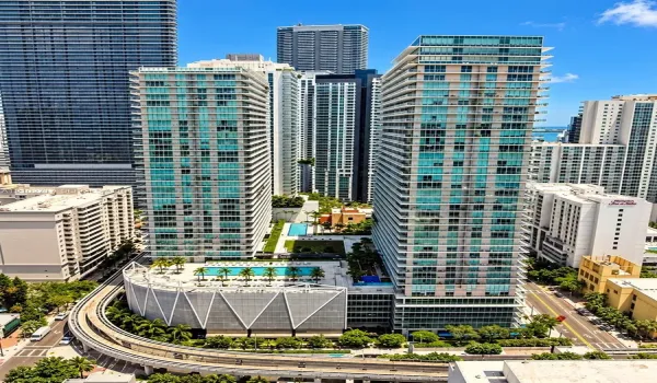 High-rise residential towers featuring floor-to-ceiling glass facades, multiple outdoor swimming pools, landscaped terrace areas, and structural parking podiums