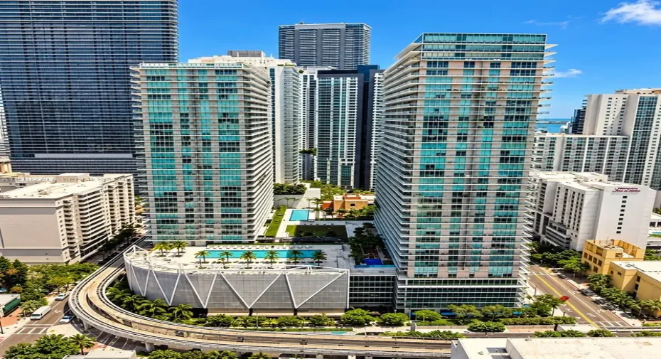 High-rise residential towers featuring floor-to-ceiling glass facades, multiple outdoor swimming pools, landscaped terrace areas, and structural parking podiums