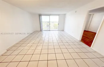 Interior space featuring large-format ceramic tile flooring, neutral walls, and a sliding glass door opening to a private balcony