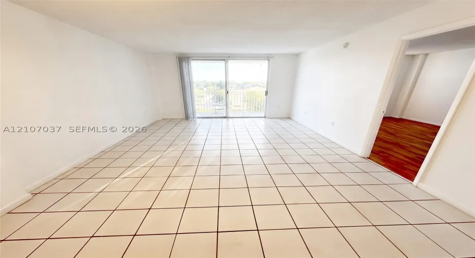 Interior space featuring large-format ceramic tile flooring, neutral walls, and a sliding glass door opening to a private balcony