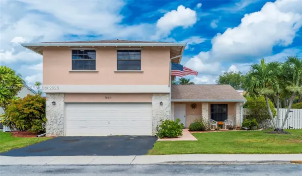 Two-story exterior featuring textured masonry accents, an attached two-car garage, low-slope roof lines, and manicured landscaping