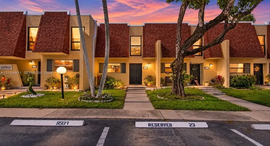 Multi-level exterior featuring mansard rooflines, stucco finish, concrete walkways, and designated parking spaces