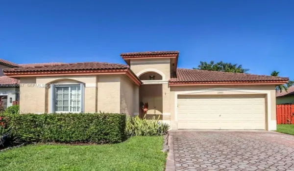 Single-story residence featuring a tile roof, stucco exterior, arched entryway, and a paved stone driveway