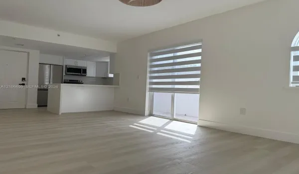 Open-concept kitchen featuring stainless steel appliances, white cabinetry, and a peninsula, complemented by wood-finish flooring and dual-tone window shades