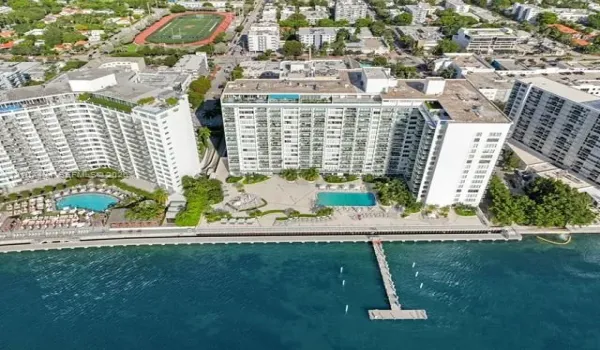 Waterfront high-rise complex featuring multiple swimming pools, a deep-water pier, paved sun decks, and manicured grounds