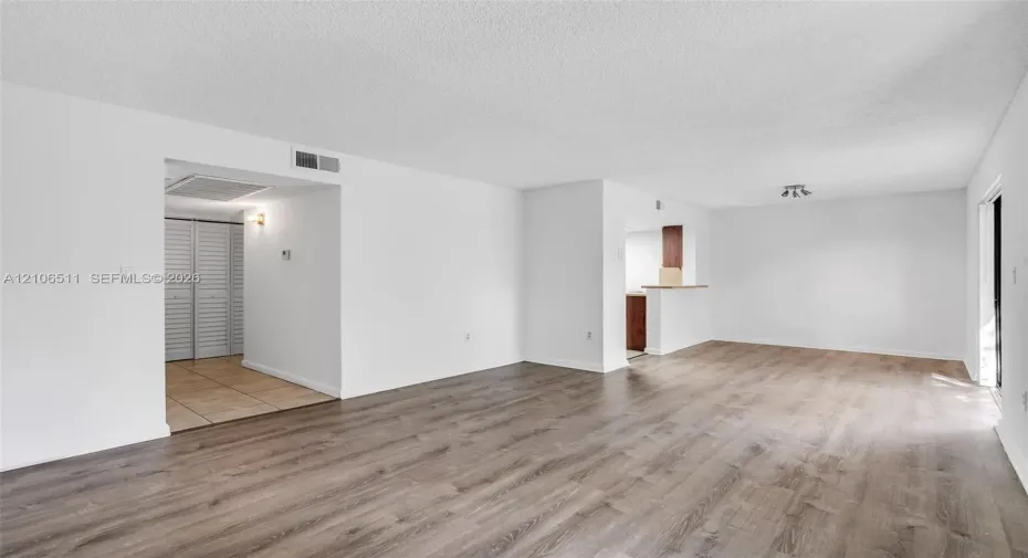 Open-concept interior featuring wood-finish flooring, neutral walls, recessed light fixture, and built-in closet with louvered doors