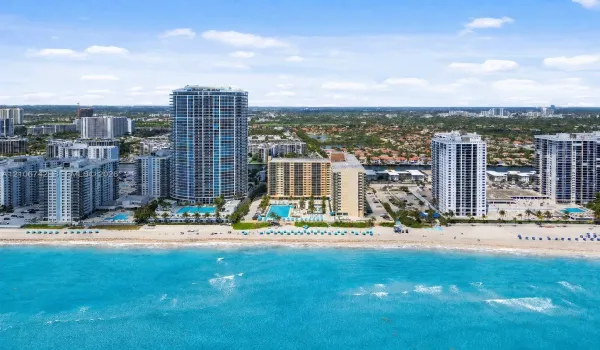 High-rise coastal property featuring direct oceanfront access, private swimming pool, landscaped grounds, and paved parking areas