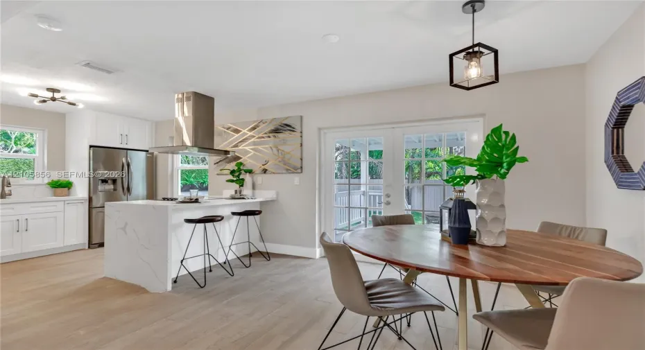 Kitchen featuring a waterfall island with a white stone-finish countertop, stainless steel range hood, built-in stainless steel refrigerator, white cabinetry, and wood-finish flooring