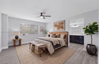 Bedroom featuring wood-finish flooring, a ceiling fan with integrated lighting, and dual-sink cabinetry with dark finishes