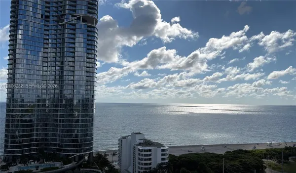 High-rise structure featuring floor-to-ceiling glass windows, oceanfront positioning, and coastal scenery
