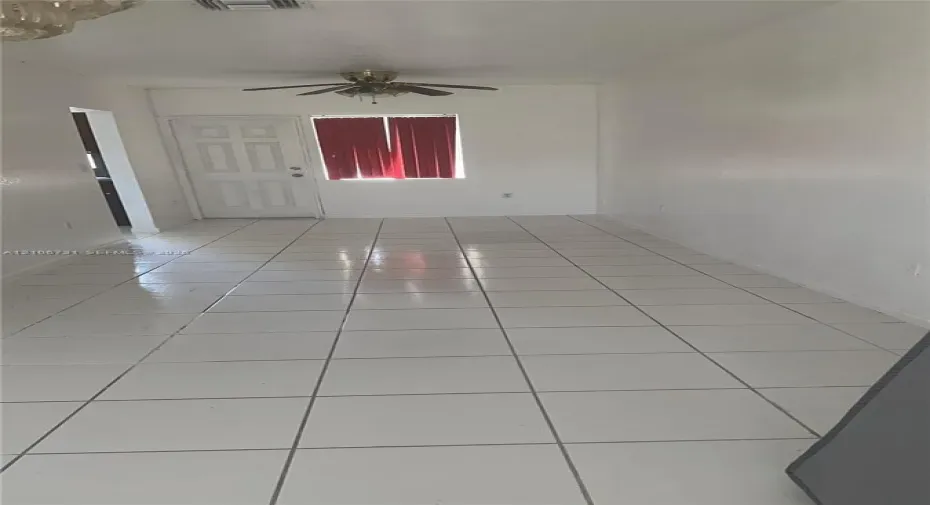 Interior space featuring white floor tiles, a six-panel exterior door, and a ceiling-mounted fan