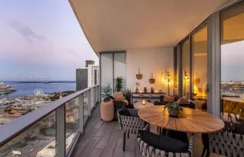 Covered balcony featuring wood-finish flooring, a glass panel railing, and expansive floor-to-ceiling windows