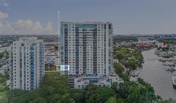 High-rise residential building featuring floor-to-ceiling glass windows, exterior balconies, and an elevated outdoor swimming pool