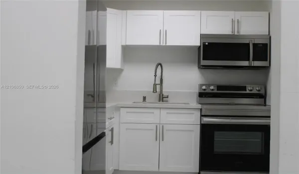 Kitchenette featuring white Shaker-style cabinetry, stainless steel appliances, a stone-composite countertop, and a gooseneck faucet