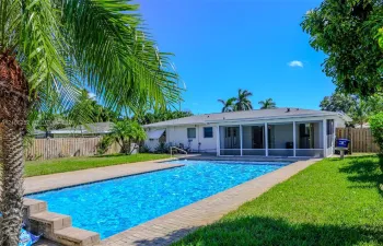 Private backyard featuring a rectangular swimming pool, paver patio surround, screen-enclosed porch, and wood privacy fencing