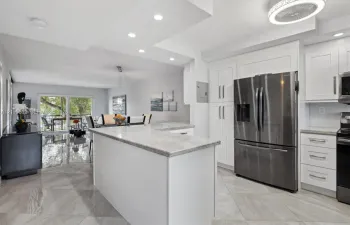 Kitchen featuring white cabinetry, stone countertops, stainless steel appliances, tile flooring, and recessed ceiling lighting