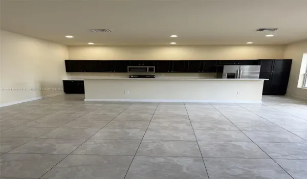 Kitchen featuring dark cabinetry, stone-finish countertops, stainless steel appliances, a breakfast bar, and tile flooring