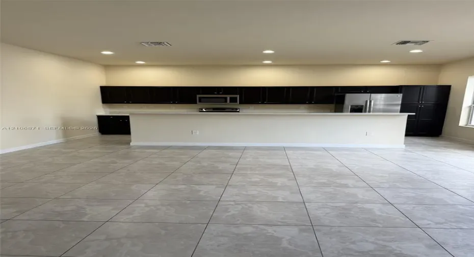 Kitchen featuring dark cabinetry, stone-finish countertops, stainless steel appliances, a breakfast bar, and tile flooring