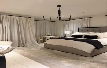 Spacious room featuring light-toned tile flooring, floor-to-ceiling drapery panels on black hardware, and a multi-arm geometric chandelier with a black finish
