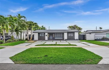 Exterior featuring a contemporary facade with a contrasting color palette, structured geometric paver driveway, manicured lawn, and mature palm trees