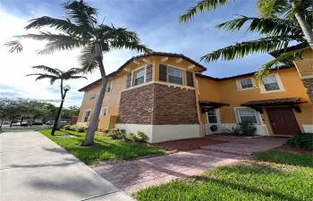 Stucco exterior featuring decorative stone veneer accents, multi-level turret architecture, barrel tile roofing details, and a paved brick walkway