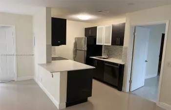 Kitchen featuring dark cabinetry with glass-panel accents, solid-surface countertops, a tiled backsplash, and stainless steel appliances