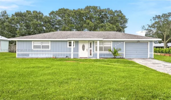 Single-story exterior featuring vertical siding, a covered entryway, an attached garage, and a concrete driveway