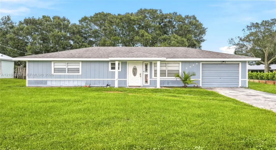 Single-story exterior featuring vertical siding, a covered entryway, an attached garage, and a concrete driveway
