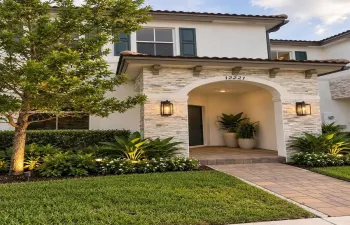 Exterior facade featuring a stucco finish, stone veneer entryway with arched detailing, barrel-tile roof, and decorative corbels