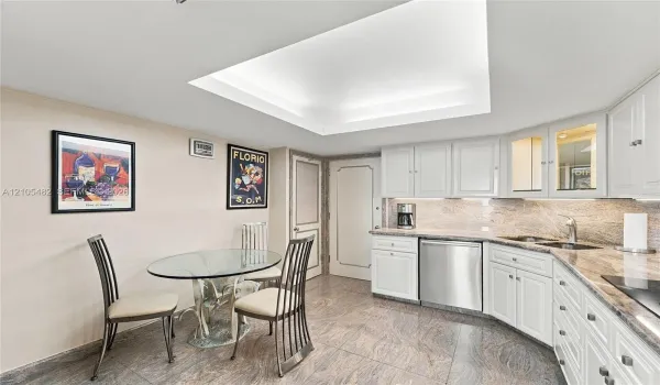 Kitchen featuring white cabinetry with glass-front display uppers, expansive stone countertops, stainless steel dishwasher, tile flooring, and a recessed ceiling cove