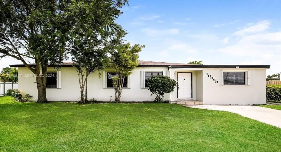 Single-story residence featuring a smooth stucco exterior, low-pitched roofline, horizontal sliding windows with exterior shutters, and a concrete driveway