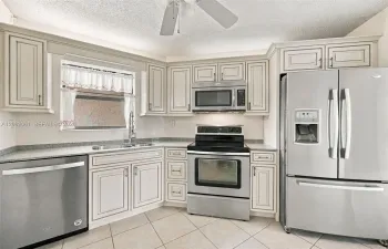 Kitchen featuring light-toned cabinetry, stainless steel appliances, speckled stone-finish countertops, and tile flooring