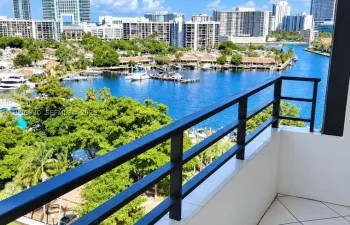 Private balcony featuring tile flooring and a black metal railing overlooking a waterfront canal and marina