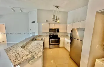 Kitchen featuring a raised breakfast bar with stone-finish countertops, white cabinetry, stainless steel appliances, and multi-light pendant illumination