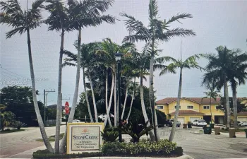 Stone Creek community entrance featuring mature palm trees, professional landscaping, a monument sign, and asphalt paving