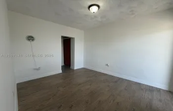 Neutral-toned walls, textured ceiling, wood-finish flooring, and semi-flush mount ceiling fixture