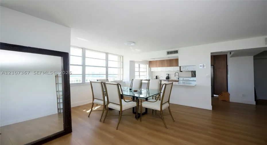 Open-concept area featuring wood-finish flooring, floor-to-ceiling windows, and a pass-through kitchen with flat-panel cabinetry