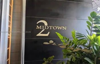 Brushed metallic building signage featuring prominent dimensional lettering against a dark, panelized facade