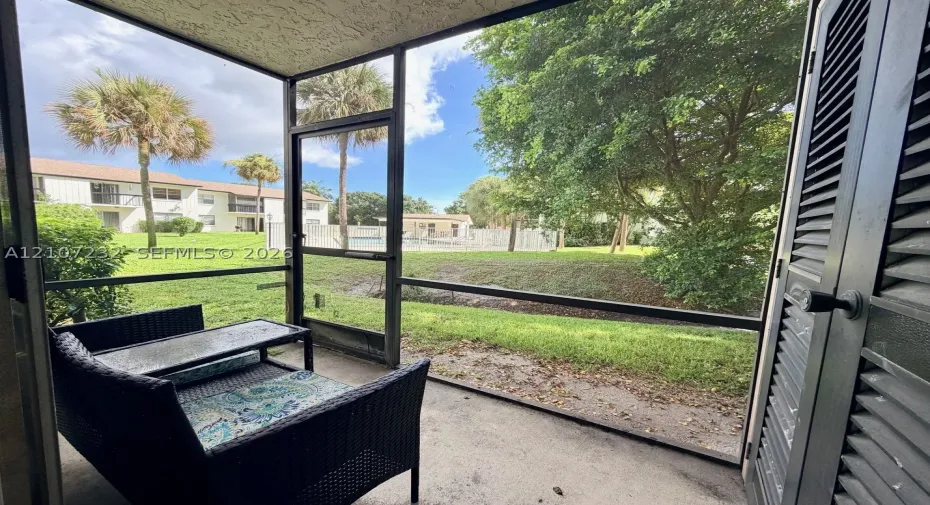 Screened-in patio with concrete flooring, louvered utility closet door, and metal frame enclosure
