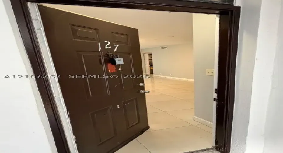 Solid core entry door with metallic hardware and large-format porcelain tile flooring