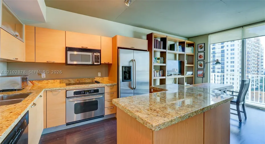 Kitchen featuring natural wood cabinetry, stone countertops, stainless steel appliances, a built-in shelving unit, and wood-finish flooring