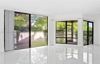 Large-format sliding glass doors, floor-to-ceiling windows, polished stone-finish flooring, and recessed ceiling lighting
