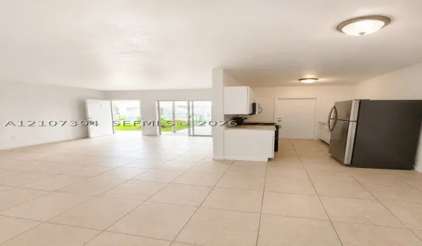 Ceramic tile flooring, white cabinetry, solid-surface countertops, stainless steel refrigerator, and glass sliding door access to exterior space