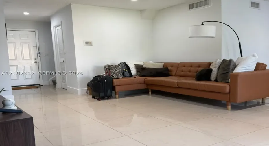 Large-format tile flooring, recessed ceiling lighting, and a six-panel entry door