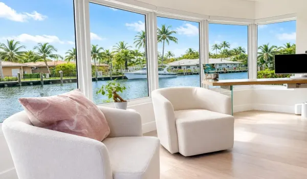 Floor-to-ceiling bay windows with water frontage, wood-finish flooring, and built-in glass-supported desk