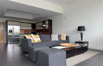 Open-concept area featuring oversized neutral floor tiling, recessed ceiling detail, and kitchen cabinetry with a two-tone finish