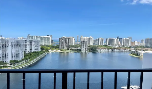 Black metal balcony railing overlooking a large lake and urban skyline