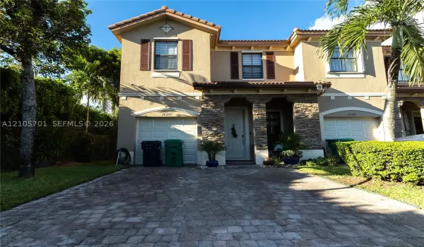 Two-story exterior featuring a stone-veneer facade, paver driveway, dual-car garage, and shutter-accented windows